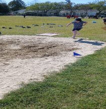 Figure 1 - Laura is making a jump on the long jump track on the grass and sand