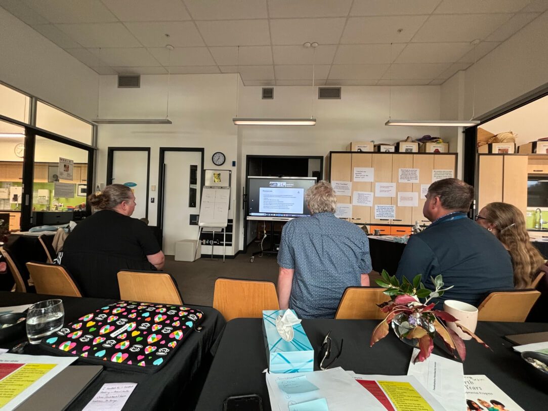 Figure 1 - The DOM and BELS team members sitting on chairs in front of a screen while taking part in professional development days based at Homai in Auckland.