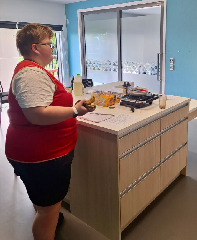 Figure 2 - BLENNZ Nelson learner standing at a table holding a sandwich